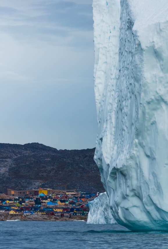 Eisberg Grönland Häuser im Hintergrund