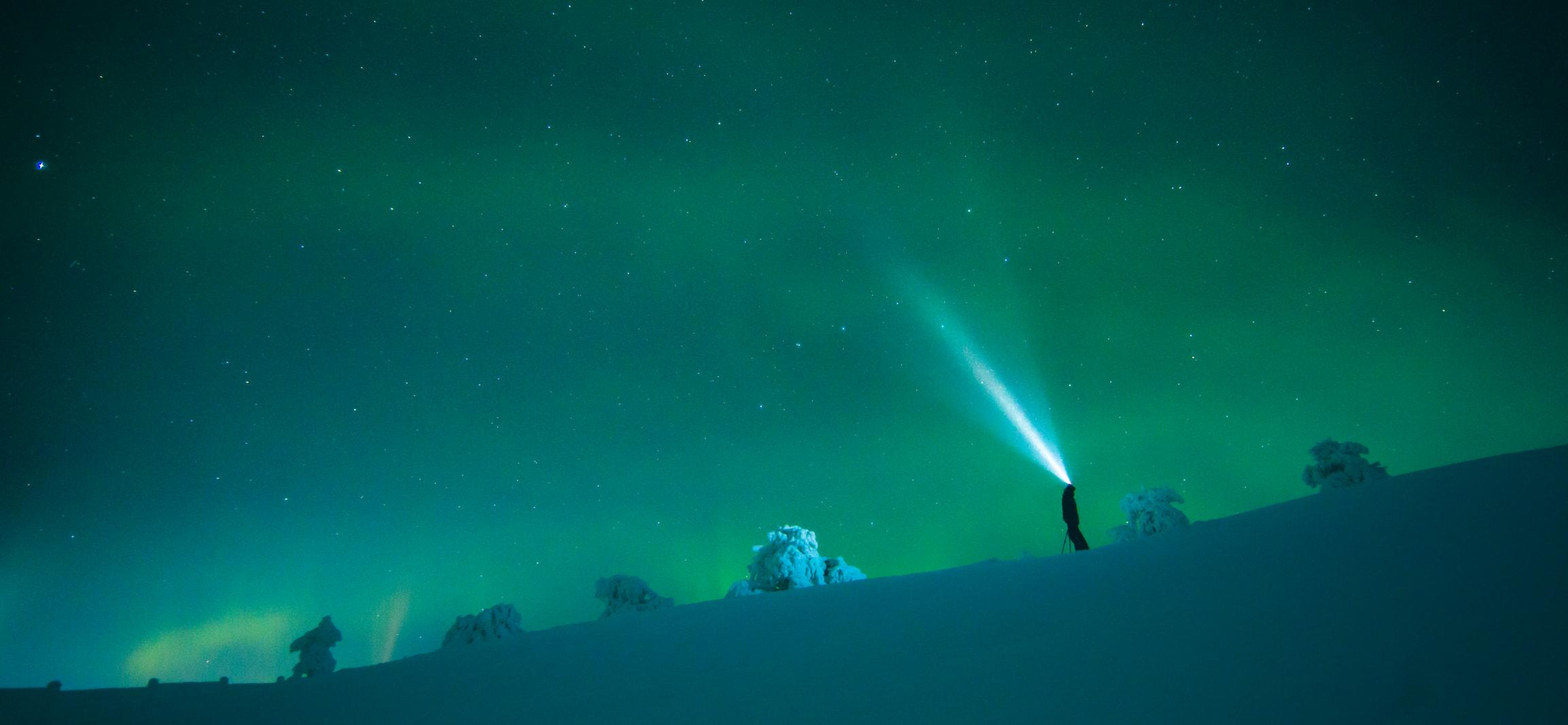 Mann mit Stirnlampe und Polarlichter