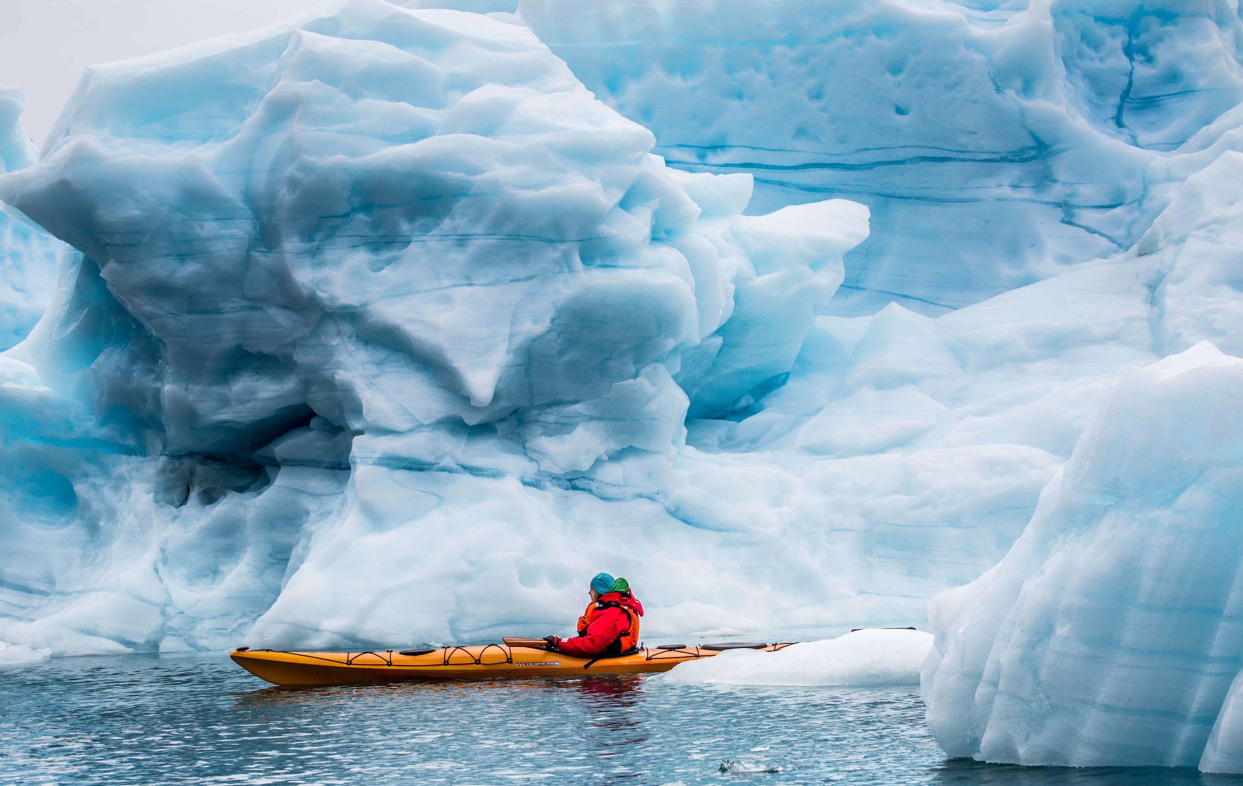 Arktis Tours Grönland erleben: Luxus-Camps zwischen Eis und Weite Kayak vor Eisberg