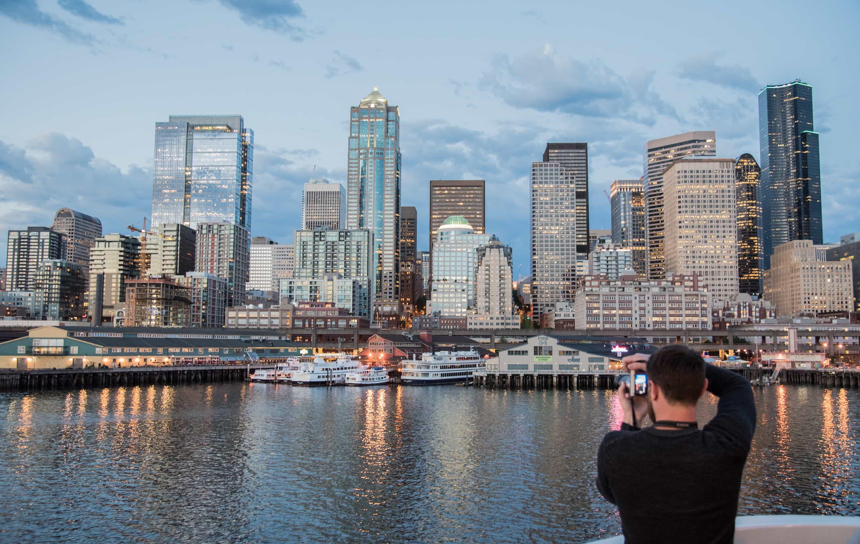 Alaska – Kreuzfahrt durch majestätische Fjorde - Mensch fotografiert die Skyline von Seattle von der Meerseite aus