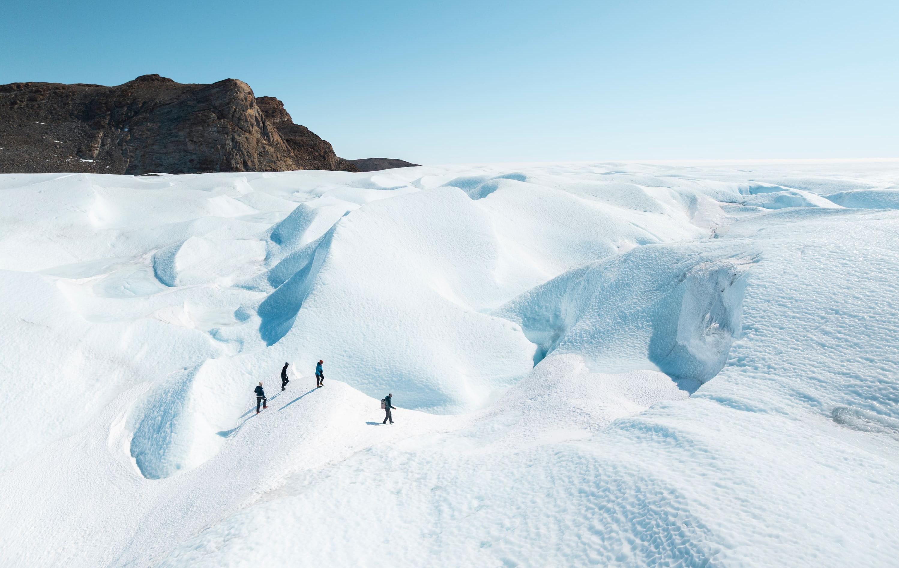 Arktis Tours - Südpol in Sicht: Antarktisreise de Luxe - Wanderer im Eis der Antarktis, schroffe Berge im Hintergrund